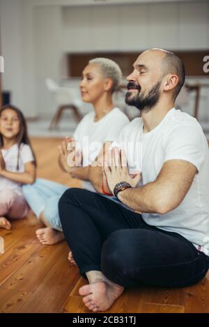 Schöne Familie meditiert zu Hause, sitzen auf dem Boden. Familie, Sport, Yoga-Konzept. Weiße Farben Stockfoto