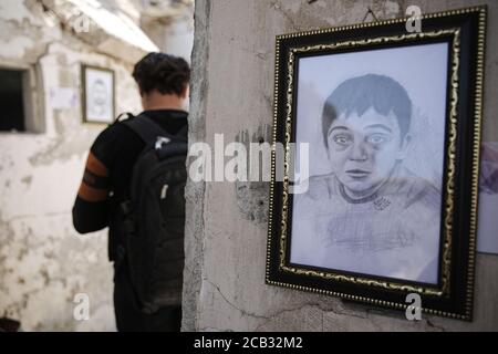 Idlib City, Syrien. August 2020. Ein Besucher besucht eine Ausstellung des syrischen Künstlers Rami Abd al-Haq in einem der beschädigten Häuser in Idlib. Die Zeichnungen zeigen Figuren und Figuren, die während des syrischen Bürgerkriegs entstanden sind und Einfluss auf die Medien hatten. Quelle: Anas Alkharboutli/dpa/Alamy Live News Stockfoto