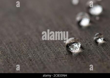 Wassertropfen auf einer flachen grauen Oberfläche Stockfoto