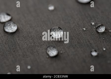 Wassertropfen auf einer flachen grauen Oberfläche Stockfoto