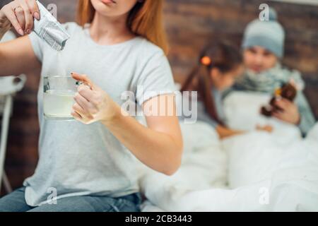 Unkenntliche Frau, die ihren Mann im Hintergrund auf dem Bett liegend behandeln wird, Eltern und Kind Stockfoto