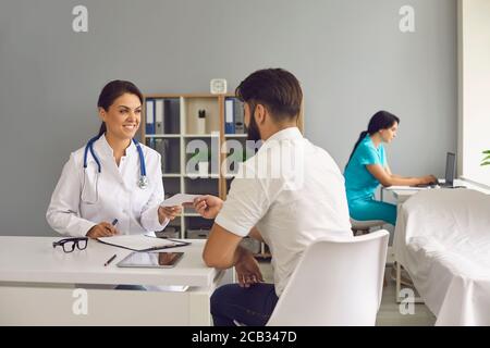 Der Arzt gibt dem Patienten ein Rezept, während er am Tisch im Büro der Klinik sitzt.Medizinische Beratung. Stockfoto