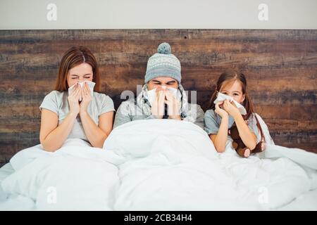 Familie, Gesundheit und Menschen Konzept . Vater und Mutter mit Vitaminen, Medizin, Mutter und kranke Kinder mit Fieber zu Hause liegen auf dem Bett Stockfoto