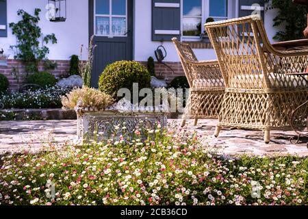 Schöner Blumengarten mit kleinem Holztor und Haus in Der Hintergrund Stockfoto