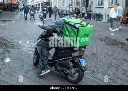 Den Haag, Niederlande. August 2020. Ein Uber isst Fahrer auf seinem Roller in der Innenstadt von Den Haag; Uber eats ist eine amerikanische Online-Bestell- und Lieferplattform für Lebenswitttel, Essen, das 2014 in San Francisco/Kalifornien gegründet wurde; in Deutschland ist der Service derzeit nicht verfügbar; Am 3. August 2020 in Den Haag/Niederlande, weltweite Nutzung Quelle: dpa/Alamy Live News Stockfoto