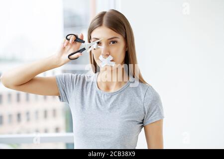 Hört auf zu rauchen, eine Frau mit verschlossendem Mund schneidet eine Zigarette mit einer Schere Stockfoto