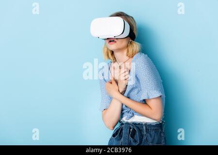 Junge und verängstigte Frau in Virtual-Reality-Headset auf blau Stockfoto