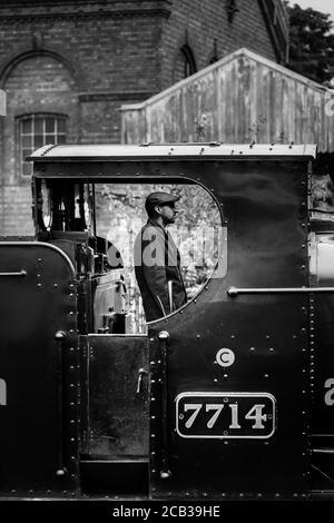 Monochrome Seitenansicht des Dampflokomotive-Fahrers in der Motorkabine, der die Abfahrt auf der Severn Valley Railway Heritage Line, Großbritannien, erwartet. Zugführer. Stockfoto