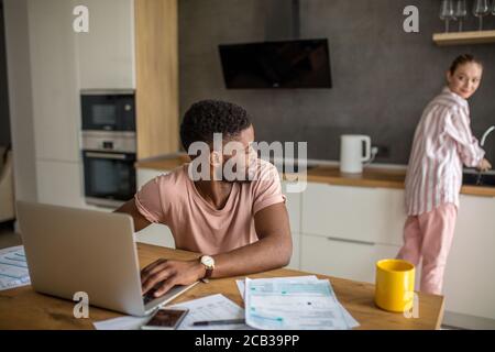 Zwanzig Jahre Paar von interracial Mitbewohner Verwaltung Haus Stromrechnungen, Berechnung Finanzen oder Budget während des Frühstücks in der modernen Küche. Stockfoto
