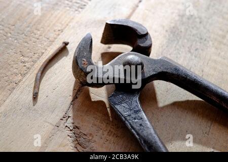 Alte Metallzange und gebogener rostiger Nagel auf verwittertem Holz Oberfläche Stockfoto