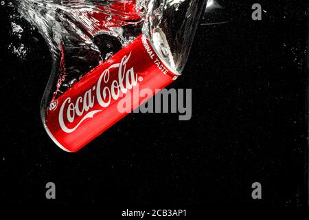 Coca Cola kann auf schwarzem Hintergrund ins Wasser spritzen Stockfoto