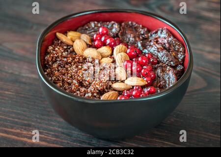 Schüssel mit roten Quinoa mit Oliven, getrockneten Tomaten, Beeren und Nüssen Stockfoto