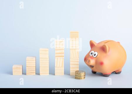 Ein Sparschwein, Münzen und Wachstumsdiagramm aus Holzblöcken Stockfoto