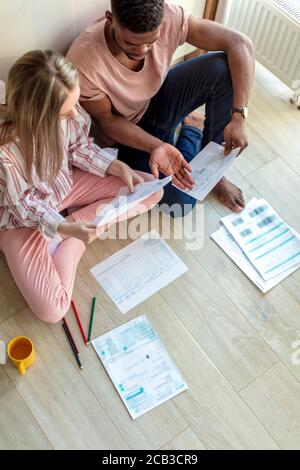 Mixed Race paar Designer entwickeln Start-up-Projekt, Pose auf dem Boden in der Küche zu Hause, umgeben von Charts und Berechnungen auf Papier Blätter. Familien Stockfoto