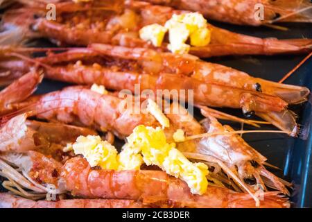 Eine Platte mit großen, King-Size-Garnelen in schwarz-weiß und monochrom. Sie bereiteten in Knoblauchbutter zum Grillen und Verzehren vor. Entkettete Garnelen, ein Blähungen Knoblauchbutter und frisch zubereitet. Stockfoto