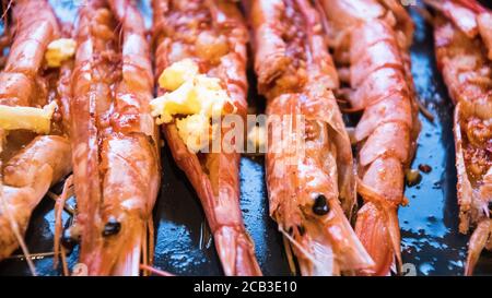 Eine Platte mit großen, King-Size-Garnelen in schwarz-weiß und monochrom. Sie bereiteten in Knoblauchbutter zum Grillen und Verzehren vor. Entkettete Garnelen, ein Blähungen Knoblauchbutter und frisch zubereitet. Stockfoto