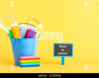 Ein Metalleimer mit Textmarker Stift und Schule Lineal auf blauem Hintergrund. Stockfoto