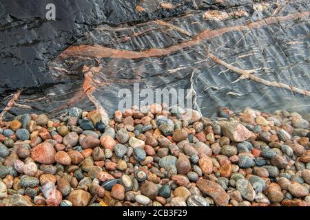Kiesel und Felswand am Strand mit unschönen Einbrüchen an der Küste des Lake Superior, Lake Superior Provincial Park, Ontario, Kanada Stockfoto