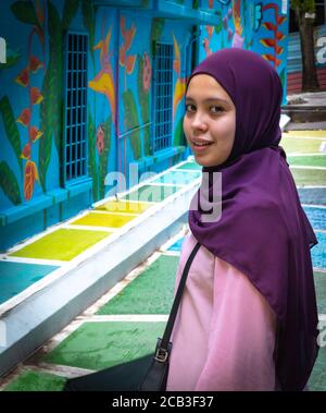 Kuala Lumpur/Malaysia, Porträt eines jungen, schönen muslimischen Mädchens in einem lila Kopftuch und einem rosa Kleid in Jalan Alor, Malaysia Stockfoto