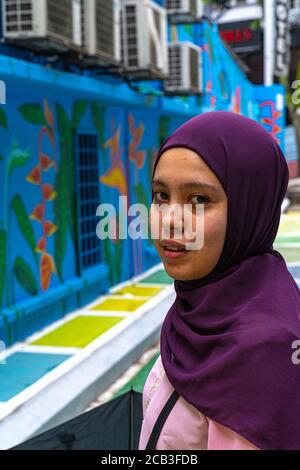 Kuala Lumpur/Malaysia/24 May 2020: Portrait eines jungen schönen muslimischen Mädchens mit purpurem Kopftuch und rosa Kleid in Jalan Alor, Malaysia Stockfoto