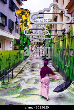 Kuala Lumpur/Malaysia/24 May 2020: Junge schöne muslimische Mädchen mit einem lila Kopftuch und einem rosa Kleid in Jalan Alor, Malaysia Stockfoto