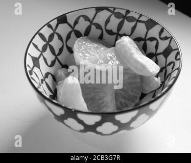 Mandarin oder satsuma in Schwarzweiß oder schwarz-weiß geschält in einer gut gestalteten Schüssel und bereit zum Serpentinen. Es gibt Kontraste und gute Texturen. Stockfoto