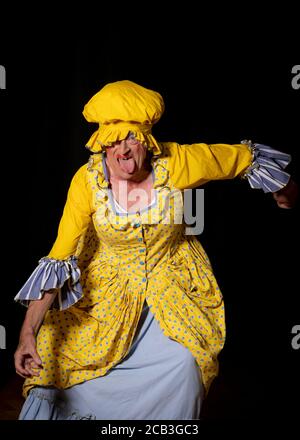 Eine hässliche Schwester in einem leuchtend gelben Kleid und passendem Hut während einer Amateur dramatischen Gesellschaft Produktion von Cinderella. Stockfoto