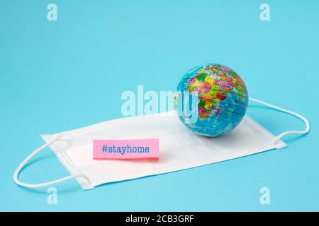 Coronavirus Prävention, Maske und Globus, zu Hause bleiben auf hellblauem Hintergrund Stockfoto