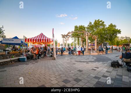 Die Leute genießen den frühen Abend im Riverfront Park in der Nähe des Rotary Fountain während des jährlichen Pig Out in the Park Festivals in Spokane, Washington, USA. Stockfoto