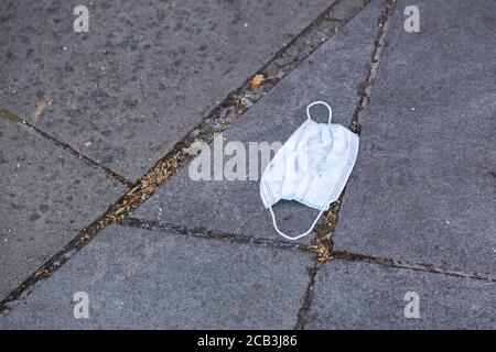 Eine weggeworfene Gesichtsmaske auf der Straße Stockfoto