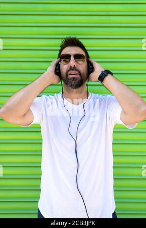 Cool trendy lustigen Bart Kerl in Kopfhörer Musik auf farbigem Hintergrund hören. Stockfoto