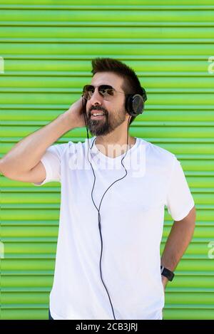 Cool trendy lustigen Bart Kerl in Kopfhörer Musik auf farbigem Hintergrund hören. Stockfoto