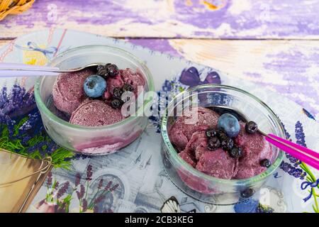 Köstliches hausgemachtes Lavendeleis in einer Glastasse mit Heidelbeeren und Waldbeeren, aus nächster Nähe Stockfoto