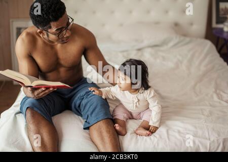 Schöne kleine Mädchen hören Papa Märchen lesen, während im Schlafzimmer ruhen. Close up Foto, kopieren Raum, Interesse, Lebensstil Stockfoto