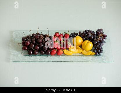 Nahaufnahme einer langen Obstplatte mit Kirschen, Erdbeeren, Trauben und Aprikosen Stockfoto