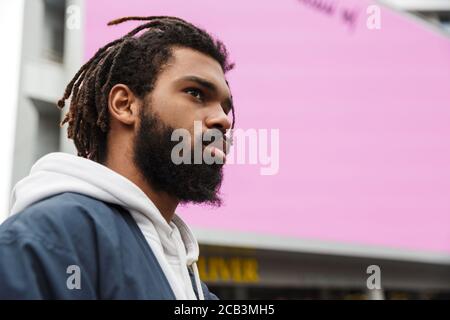 Bild von einem schönen seriösen jungen Mann, der im Freien sucht Beiseite Stockfoto