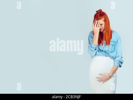 Depression vor der Geburt. Schöne junge Frau gestresst warten auf Baby und mit gesundheitlichen Problemen suchen müde und erschöpft isoliert auf hellblau. Stockfoto