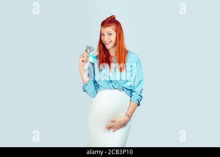 Schöne Ingwer Frau mit Bauch hält einige Kreditkarten glücklich mit Geld sparen, während lächeln aufgeregt an der Kamera auf hellblau. Ich habe meinen sta erhalten Stockfoto