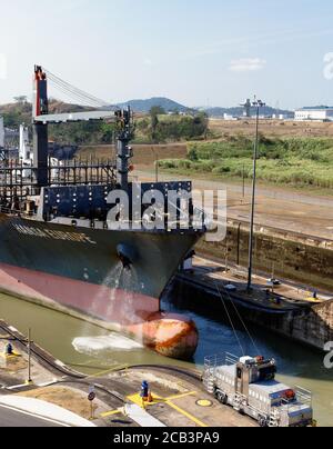 Der Bug des Containerschiffes Hansa Europe in die Miraflores Schleuse auf dem Panamakanal, Panama, niedrige Wasserseite durch elektrische Maultierschlepper geführt. Stockfoto