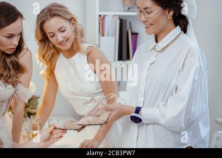 Junge Frau zeigt Designer-Schuhe für Damen in Kleidern, Präsentation von neuen Schuhen im Salon. Design, Feier, Kleidung, Schuhe, Schuhkonzept Stockfoto