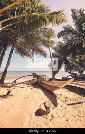 Kleines Fischerboot an einem tropischen Strand, retro farbiges Bild. Stockfoto