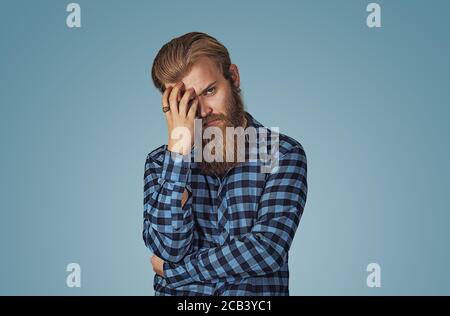 Nahaufnahme Porträt traurig junge gut aussehende bärtige Mann mit besorgt negativ gestressten Gesichtsausdruck Blick nach unten. Hipster Männchen mit Bart in blau karierten che Stockfoto