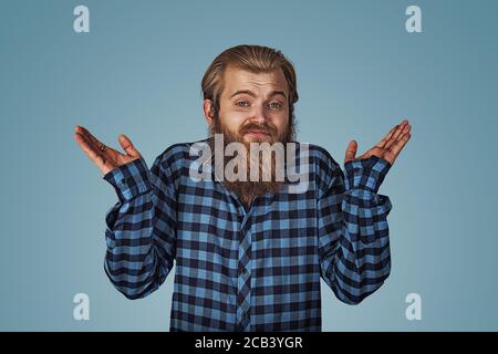 Ignoranz und Arroganz. Junger Mann zuckt die Schultern, wer kümmert sich so was. Hipster Männchen mit Bart in blau kariert kariertes Hemd isoliert auf blauem Nieten Stockfoto