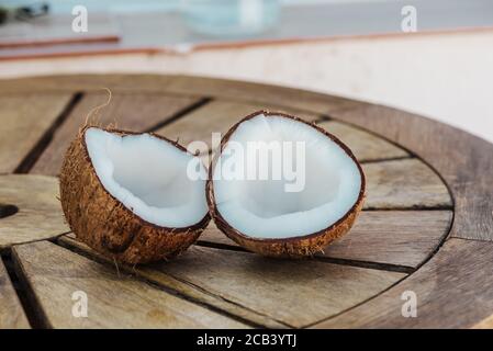 Hälften Kokosnüsse: Selektiver Fokus von frischen leckeren Kokosnuss Hälfte auf Holztisch, im Freien, niemand Stockfoto