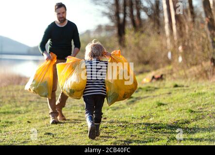 Vater mit kleinen Sohn sammeln Müll im Freien in der Natur, plogging Konzept. Stockfoto