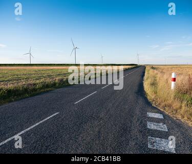 Straßen- und Windturbinen in der ländlichen Landschaft Nordfrankreichs Stockfoto