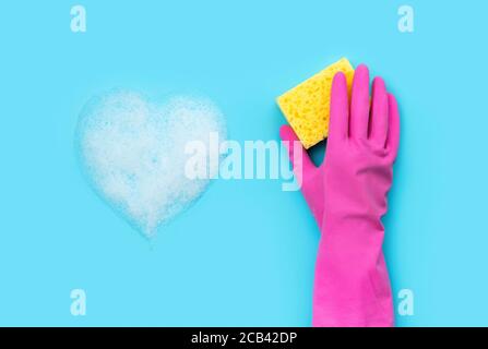 Frauenhand in rosa Gummihandschuh waschen von Schwamm blau Hintergrund Stockfoto