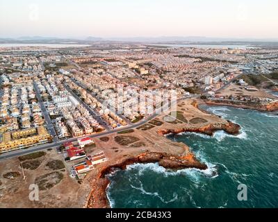 Luftpanoramabo von Torrevieja Stadtbild, felsige Küste Mittelmeer bei Sonnenaufgang, Salzsee oder Las Salinas, Bildansicht von oben. Pro Stockfoto