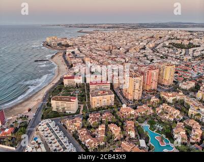 Luftpanoramabo von Torrevieja Stadtbild, felsige Küste Mittelmeer bei Sonnenaufgang, Salzsee oder Las Salinas, Bildansicht von oben. Pro Stockfoto