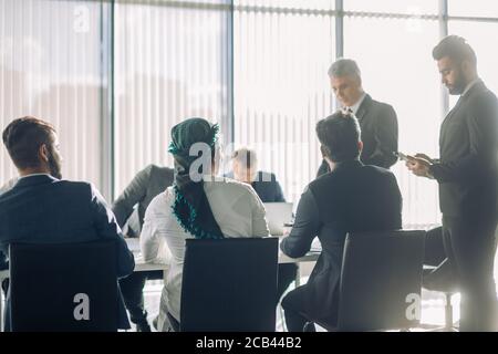 Team verschiedener mittleren Alters multiethnischen männlichen Investoren, die von den älteren im Alter von erfahrenen Regisseur, die Zusammenarbeit bei der Entwicklung gemeinsamer Investitionen proj Stockfoto